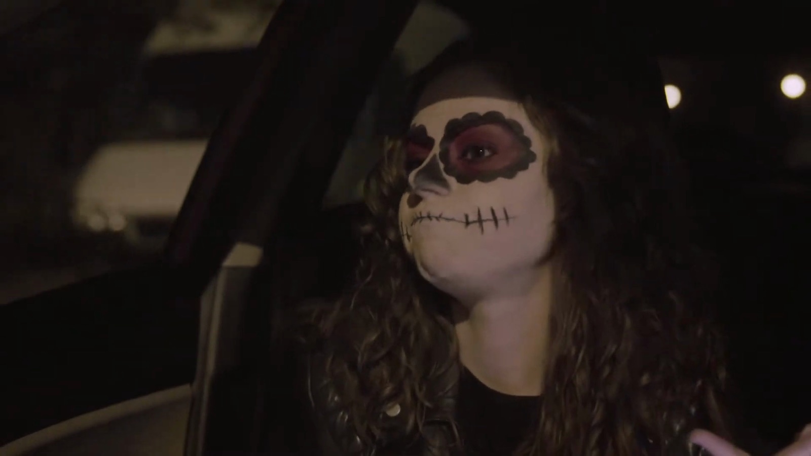 Two friends in costume make-up drive to a Halloween party.