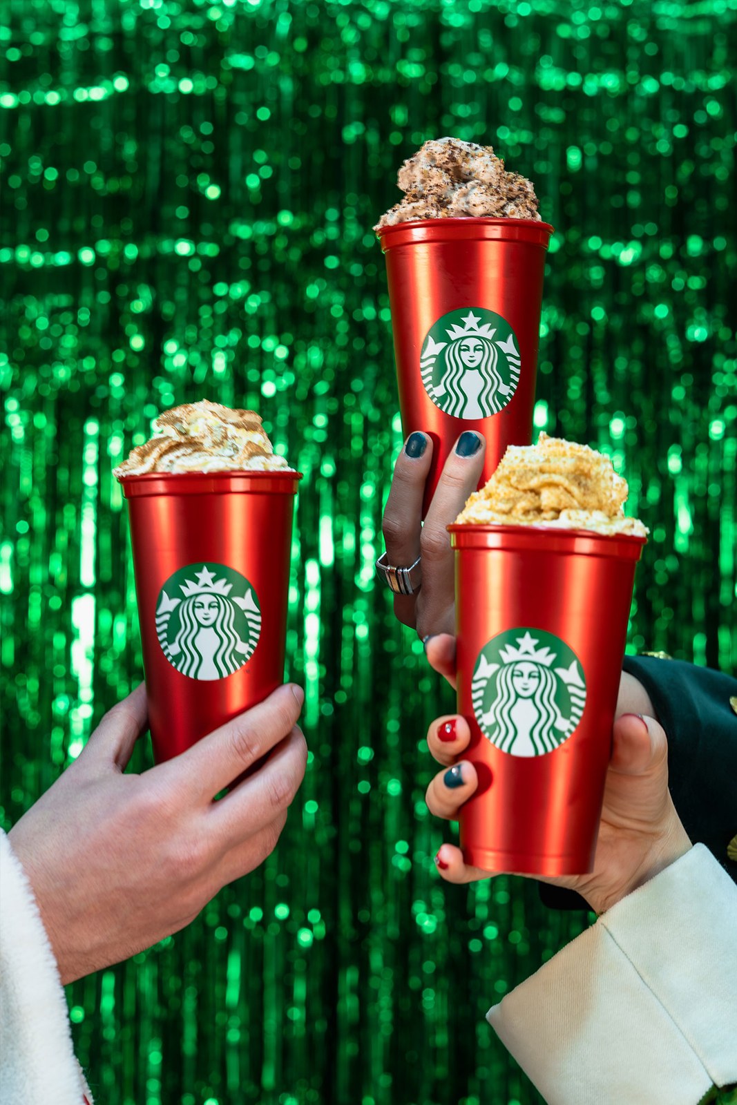 Three hands, three red cups: Santa, the Grinch and the elf in the key visual.