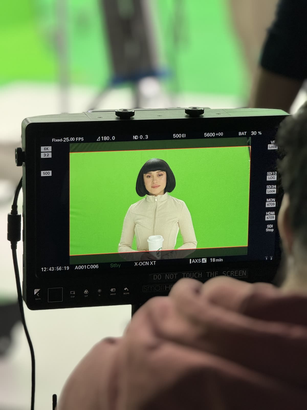 On set, 3 March 2024: Irina Rimes on the camera monitor in front of the green screen, cup in hand.