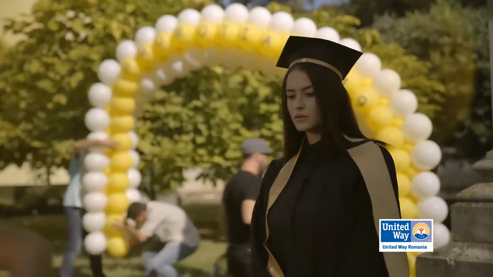 Behind the graduate, the crew is already clearing the set.
